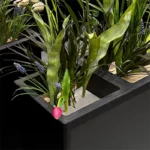 Hoekdetail plantenbak zwart drievoudig met kunstbloemen